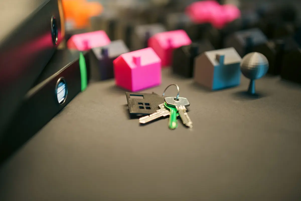 A set of house keys and small wooden house models resting on a desk.